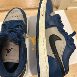 Nike Air Jordans i blått och grått - Snygga Nike Air Jordans i en fräsch kombination av blått och grått. Skorna har en klassisk design med snörning och den ikoniska Nike-loggan på sidan. Perfekta för dig som vill ha stil och komfort i ett.