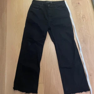 Svarta jeans med rå kant - Snygga svarta byxor från Gallucks med en rå kant vid bensluten, kan sy upp dem vid efterfrågan. Byxorna har en rak passform. Perfekta för en stilren look. W: 40cm L:107cm benöppning: 26cm
