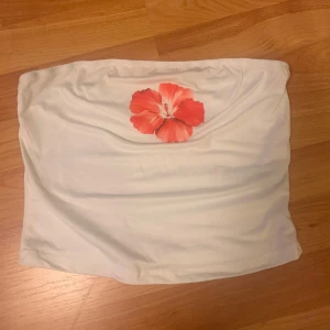 Vit tubtopp med röd blomma från Shein - Säljer en vit tubtopp från Shein med en stor röd/rosa blomma framtill. Storlek s.