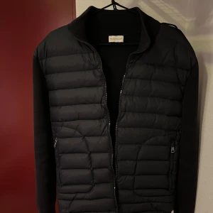 Marinblå  dunjacka från Moncler - Snygg svart dunjacka från Moncler med quiltad design och dragkedja framtill. Jackan har långa ärmar och en diskret logga på sidan. Perfekt för kyligare dagar.