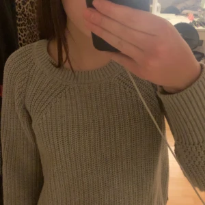 Grå stickad tröja från House of Lola - Mysig grå stickad tröja från House of Lola i storlek XS. Tröjan har en rund halsringning och långa ärmar med ribbade muddar. Perfekt för kyligare dagar.