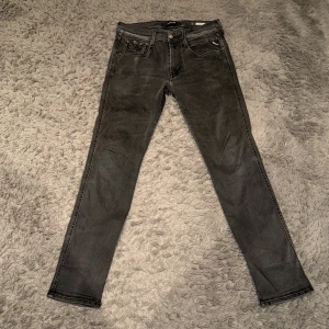 Grå jeans från Replay slim fit - Snygga grå jeans från Replay i modellen Anbass. De har en slim passform och klassisk femficksdesign med dragkedja och knapp. Perfekta för en stilren look. Först till kvarn!         Storlek L30 W31