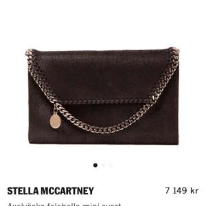 Svart axelväska från Stella McCartney - Snygg svart axelväska från Stella McCartney med kedjedetaljer och en elegant kuvertform. Väskan har en praktisk axelrem och ett stilrent innerfoder. Använd ca 5 gånger, säljer pga att den tyvärr inte kommer till användning. Nypris: 7 149kr, mitt pris 5 000kr