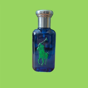Ralph Lauren parfym - Snygg blå parfymflaska från Ralph Lauren med en grön polo-spelare på framsidan och en stor gul siffra 1 på baksidan. Flaskan har en elegant silverfärgad kork. Perfekt för den stilmedvetna! Den är fräsch och fin!