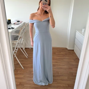 Ljusblå långklänning - balklänning  - En fin ljusblå långklänning med offshoulder-design. Använd en gång på ett bröllop, så den är som ny. Köpt på Nelly och har storleken 36.