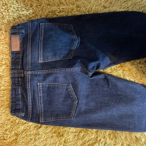 Mörkblå jeansbyxor - Snygga mörkblå jeansbyxor med klassisk femficksdesign och knappgylf. Perfekta för en avslappnad stil. Passar bra till både t-shirt och skjorta.