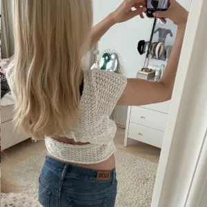 Topp  - Säljer en söt vit stickad topp med korta ärmar och volangdetaljer. Toppen är croppad och har ett fint mönster som ger en bohemisk känsla. Perfekt för varma dagar! Från Zara, slutsåld!