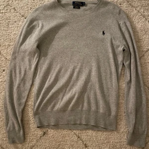 Grå tröja från Polo Ralph Lauren  - Säljer en stilren grå tröja från Polo Ralph Lauren i storlek S med slim fit. Tröjan är tillverkad i mjuk pima bomull, bra skick möjligt lite stor i halsen.
