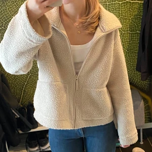 Beige teddyjacka med dragkedja - Intressekoll på teddyjacka med dragkedja framtill. Perfekt för kyliga dagar med sin fluffiga och varma design. Jackan har en avslappnad passform och långa ärmar. Pris kan diskuteras 
