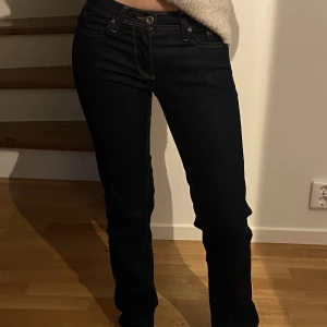 Mörkblåa jeans - lågmidjade/midrise mörkblåa jeans från Hilfiger Denim, skulle säga att de är mer lowrise än midrise. Har fina sömmar på både framsida och baksida. Aldrig använda. Storlek 24/32 modell MID RISE STRAIGHT. 