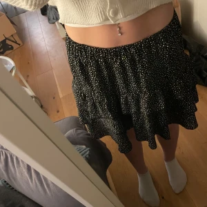 Svart prickig kjol - Säljer en fin prickig kjol. Kjolen har en volangdetalj och är perfekt för en trendig look. Den är i storlek M och har en bekväm passform. Den är i nyskick då jag inte använt den. Passar perfekt till sommaren✨☀️✨