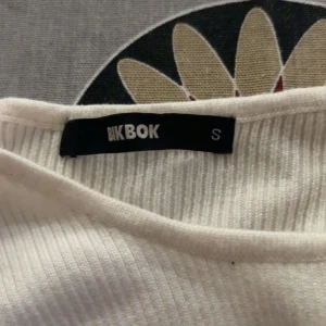 Vit ribbad topp från Bik Bok - Säljer en stilren vit ribbad topp från Bik Bok i storlek S. Toppen har en rund halsringning och långa ärmar, perfekt för lager-på-lager eller som den är. Ett mångsidigt plagg för garderoben!