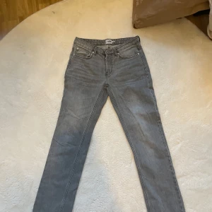 Grå jeansbyxor - Snygga grå jeansbyxor med en klassisk femficksdesign. De har en smal passform och är perfekta för en stilren look. Byxorna har en knapp stängning.