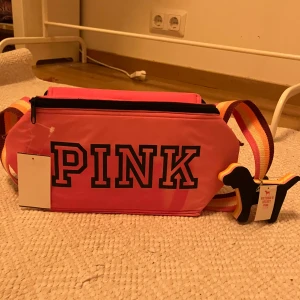 Victoria Secret Pink Väska - Snygg rosa axelväska från Victoria Secret, Pink, med ett stort tryck på framsidan🩷 Oanvänd med prislappen kvar (dock köpt på myrorna)<3