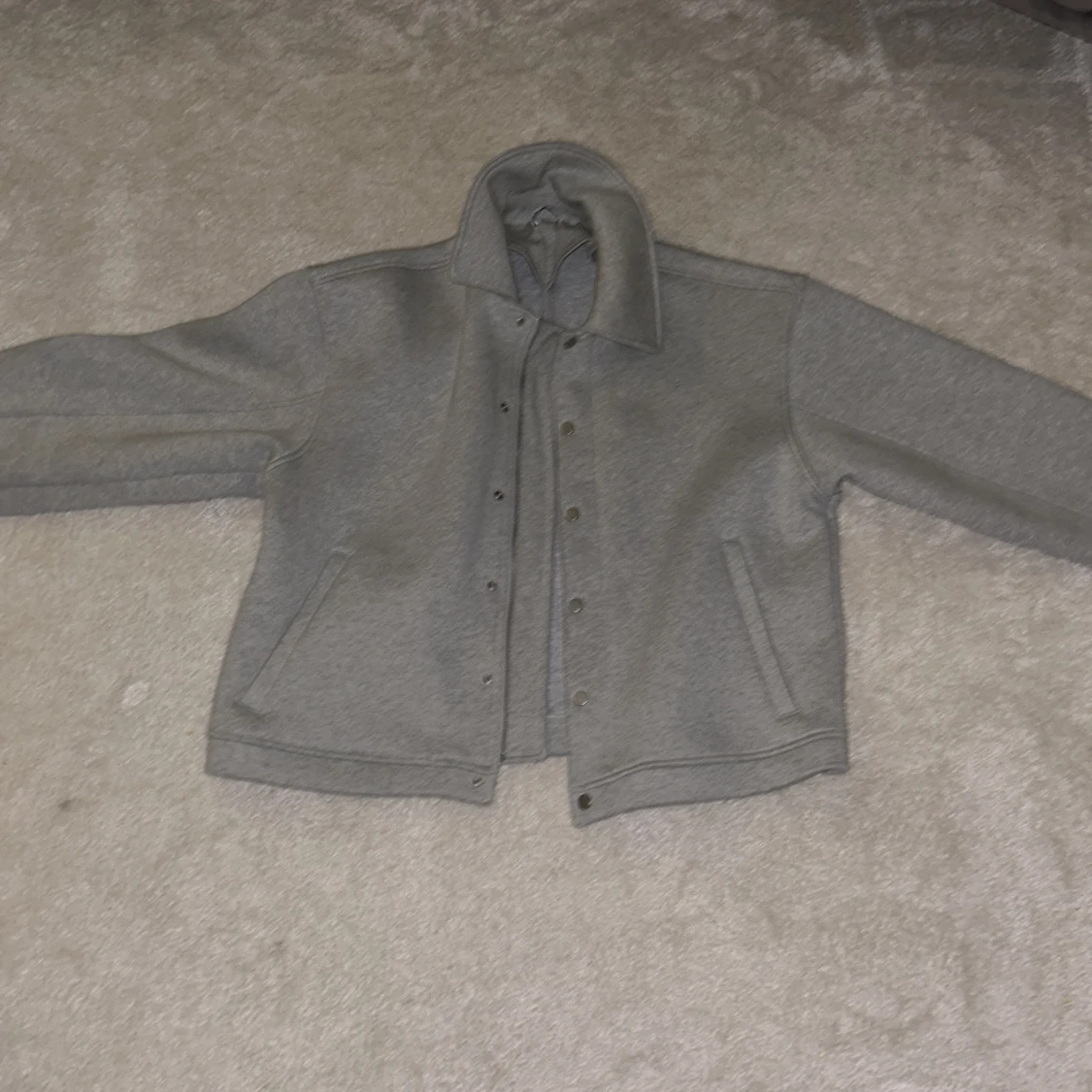 Grå jacka med dragkedja och knappar