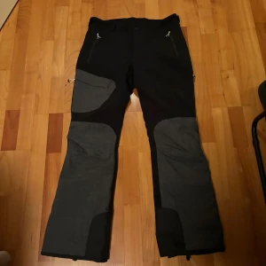 Täckbyxor från Five Seasons - Säljer ett par svarta och grå täckbyxor från Five Seasons. Byxorna har dragkedjor och praktiska fickor, perfekta för utomhusaktiviteter. De är designade för att hålla dig varm och bekväm under kalla dagar i skidbacken. Skriv vid funderingar🤩
