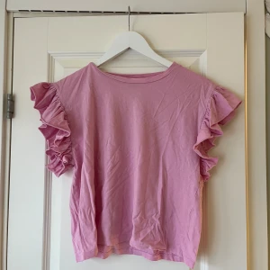 Rosa topp med volangärmar från Zara - Säljer en söt rosa topp från Zara med volangdetaljer på ärmarna💗 Toppen har en rund halsringning. Den är tillverkad i ett mjukt material som känns skönt mot huden💗