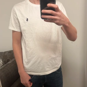 Vit t-shirt från Ralph Lauren - Säljer en klassisk vit t-shirt från Ralph Lauren med det ikoniska broderade logotypen på bröstet. Perfekt basplagg för alla tillfällen. Skön och stilren design. Pris kan diskuteras 