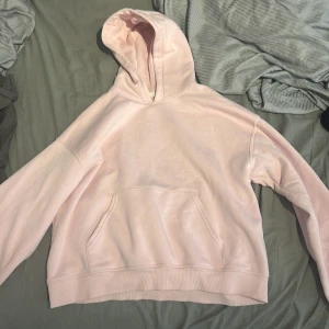 Ljusrosa hoodie från Gina tricot  - Säljer en mysig ljusrosa hoodie med känguruficka framtill. Perfekt för en avslappnad stil. Den har en klassisk design med huva och långa ärmar.