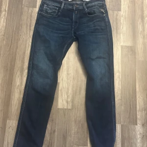 Mörkblå jeans från Replay - Snygga mörkblå jeans från Replay med klassisk femficksdesign och knappgylf. Perfekta för en avslappnad stil. Märkeslogga på bakfickan och bältesögla.