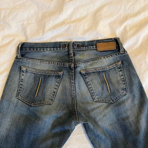 Snygga flared low-waisted jeans - Skit snygga jeans med detaljer på fickorna, midjemåttet är 38 cm rakt över och innerbenslängden är 86 cm. Dragskedjan är sönder men det märks inte när man har på sig dem!🙂