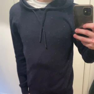 Mörkblå cashmere hoodie  - Säljer en stilren mörkblå hoodie från Sayless i mjuk cashmere. Perfekt för både vardag och fest🍾. Den har en justerbar huva med snören och långa ärmar. Defekt i bild 4 sitter i armhålan på vänster arm.