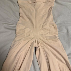 Beige oneshoulder bodysuit från Spanx , mycket slimmande. - Säljer en beige oneshoulder bodysuit från Spanx. Perfekt för att skapa en slät siluett under kläder. Materialet är mjukt och stretchigt för en bekväm passform. Passar bra till olika outfits och tillfällen.