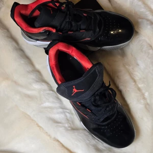 Svarta Jordans med röda detaljer - Snygga svarta Jordans "Stay Loyal" med röda detaljer och vit sula. Skorna har klassisk snörning och den ikoniska Jumpman-loggan i rött. Perfekta för dig som vill ha en stilren och sportig look.