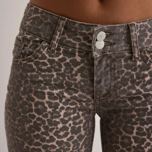 Low waist leopard jeans - Snygga leopardmönstrade jeansbyxor med hög midja och bootcut-stil. Perfekta för att ge en trendig touch till din outfit. Byxorna har två knappar och dragkedja framtill samt fickor både fram och bak.