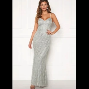 Klänning - Elegant glittrig silverklänning med v-ringad hals och figurnära passform. Perfekt för festliga tillfällen.