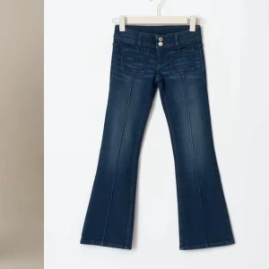 Mörkblå bootcut jeans - Snygga mörkblå bootcut jeans med låg midja och dubbla knappar. De har framfickor och en stilren design som passar perfekt till olika tillfällen. Jeansen är bara använda ca 5 gånger.