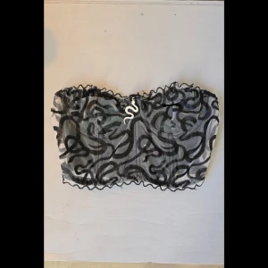 Svart och vit korsett - Korsett i svart och vitt med ett abstrakt mönster. Toppen har en elastisk kant upptill och nedtill för en säker passform. Och går att ställa in i ryggen. Hund finns i hemmet.