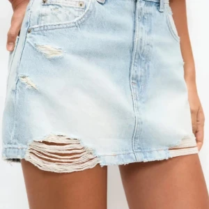 Ljusa jeanskjol från Pull&Bear - Snygg ljusblå jeanskjol från Pull&Bear med slitna detaljer. Använd fåtal gånger 