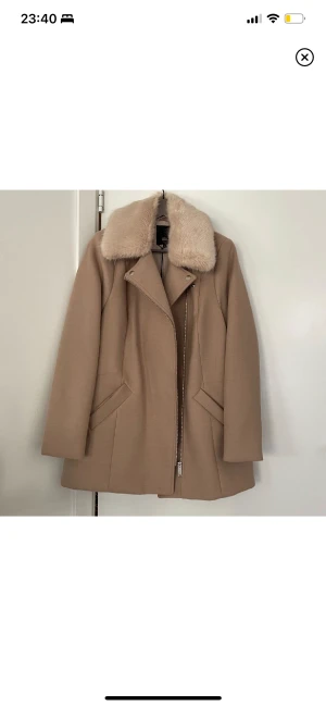 Jacka 38 - Snygg jacka/kappa från River Island. Storlek UK12/EUR38. Fin fuskpälskant som också kan tas av. Alla lappar sitter kvar, påse med extraknapp osv.. Nyskick & en riktigt fin modell✨🌿