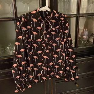 Blus med knyt  - Fin blus med flamingos i bra skick. Söt är med volang. 
