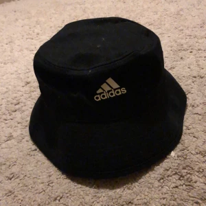 Adidas bucket hat - Hej! Säljer nu denna adidas bucket hat jag fick i present men som var för stor för mig. Den är helt ny med prislapp kvar. Skick 10/10. Buckethaten är one sized men passar large. (se bild 3).