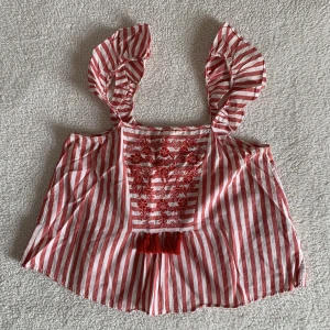 ZARA BRODERAD SOMMAR TOPP MED TASSELS - Så himla söt topp från ZARA med broderade detaljer, tassels och volangkänsla vid axelbanden. Två tassels har lossnat (vänster och höger sida saknas) men inget som man tänker på. 🌻