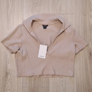 Crop top med krage  - Oanvänd kortärmad beige crop top från Monki. 🤎