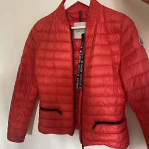 Moncler jacka  - En röd moncler jacka i storlek xs. QR-kod finns. Säljer pga att den inte kommer tlll användning. Inga defekter.  Skriv för fler bilder. Ljuset gör inte färgen riktigt rätt. Köparen står för frakten, inga retuer.🥰