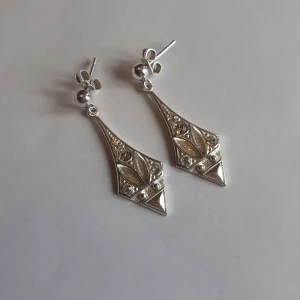 Silver örhängen  - Örhöngen i äkta silver med 4 stenar. Triangelformade nertill och helt oanvända. Längd 3 cm och bredd 1 cm. Frakt: 15 kr