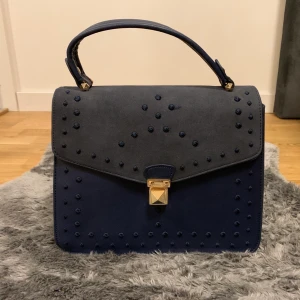 Väska  - Mörkblå sammetväska på framsidan och skinn på baksidan. Gulddetaljer. Väldigt unik väska som är köpt i Dubai. Aldrig använd, plast finns kvar. Fler bilder skickas om så önskas. 
