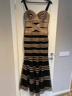 Aftonklänning - Jättefin aftonklänning i storlek 38/M.  Storleken på klänningen är angivet som något större, men passar bra till en storlek 38/M.  Hängsel på klänningen har jag sytt, så man kan tar bort de om man vill.   Färgen är guld och svart. Den svarta materialen är