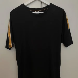 T-shirt  - Svart T-shirt med stripes längst med ärmarna