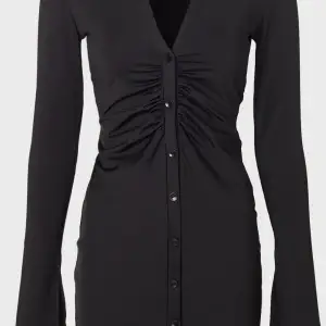 En svart klänning med knappar som är långärmad och har slits vid ärmarna. Den är medellång i storlek L är för stor för mig därför behöver jag sälja den, har dock använt den en gång. 