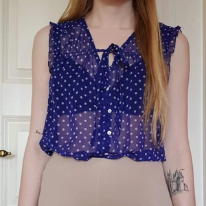 Prickig blus - Blå, prickig, genomskinlig blus, med knytband och volanger.