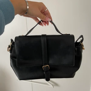 Svart handväska  - Svart handväska med gulddetaljer. Finns även långt band. 