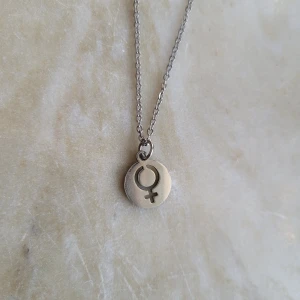 Halsband med kvinnotecken! - Gulligt halsband med litet kvinnotecken!! I rostfritt stål. Använt några få gånger men i fint skick. Frakt tillkommer med 1 frimärke! 