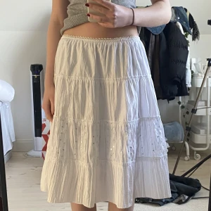 Lågmidjad vit kjol  - Jätte söt midi kjol med spets kant och paljett detaljer. Mycket stretchig så passar flera storlekar. Har två lager så ej genomskinlig och har två remmar (för att dra ett band genom tror jag, dm för tydligare bild). 