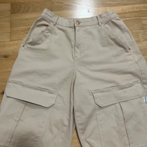 Beige cargobyxor  - Ett par cargobyxor från Bershka. Storlek 38 men passar nog större pga den elastiska midjan. Använt ett par gånger men i bra skick :)