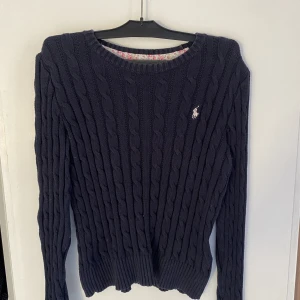 Kabelstickad tröja  - En marinblå kabelstickad tröja från Ralph Lauren, köpt från kidsbarndstore i storlek 8-10. Använd Max 2 gånger 